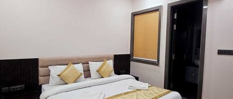 A hotel room with a bed, a ceiling fan, an air conditioning unit, a wardrobe, and a television.
