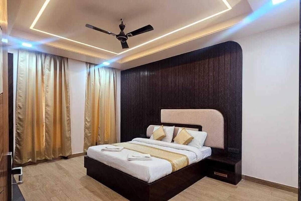 Une chambre moderne avec un grand lit, des luminaires au plafond, un ventilateur de plafond et un plancher en bois.