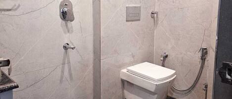 A modern bathroom with a shower, toilet, and a marble wall.