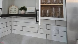 A kitchen with white cabinets, black countertops, and a built-in shelf with glassware. - Everything within 1 mile (Durham)