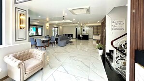 A spacious lobby with a marble floor, a plush sofa, and a reception desk.