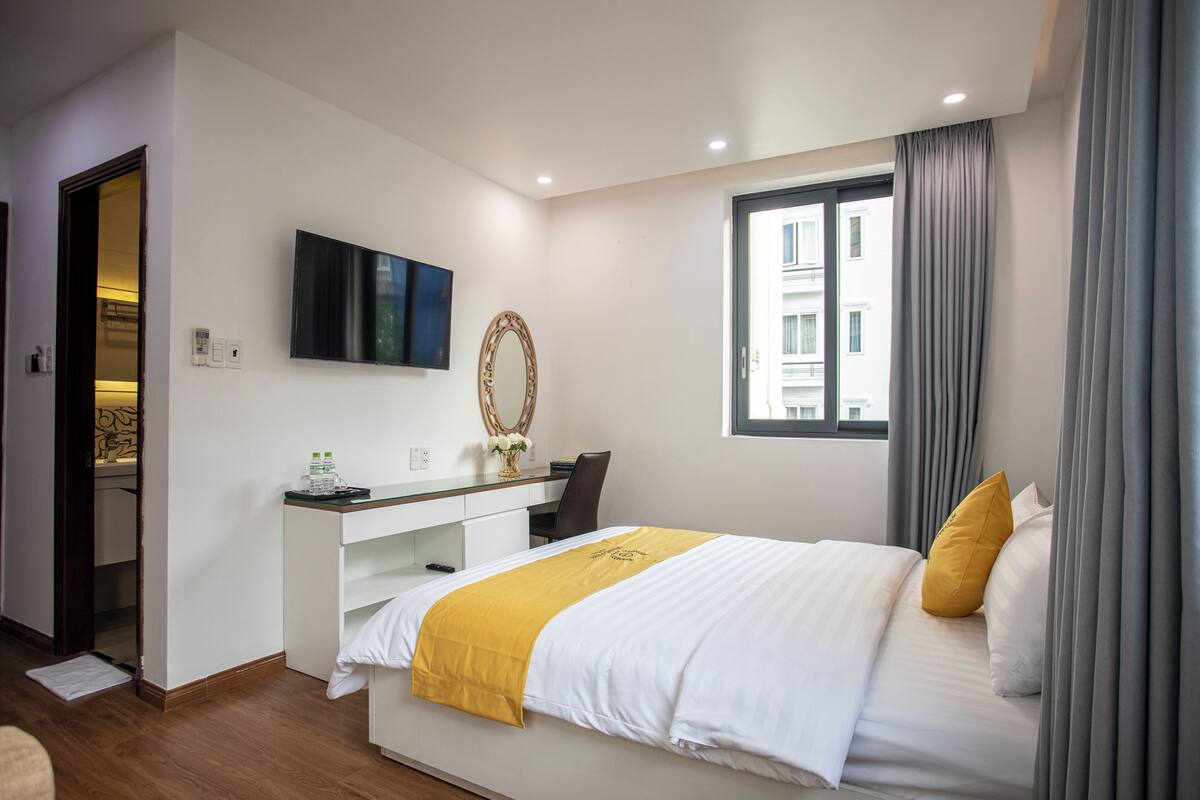 Quarto de hotel moderno com cama, escrivaninha e uma grande janela.