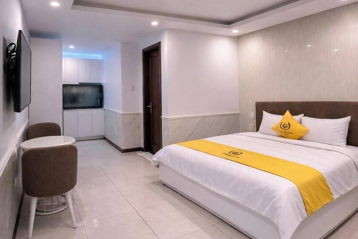 Quarto de hotel com cama, televisão, mesa pequena e uma cadeira.