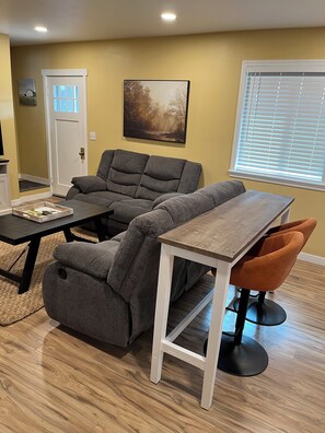 A living room with a gray sectional sofa, a wooden coffee table, and an orange chair. - Sequim Getaway (Sequim)
