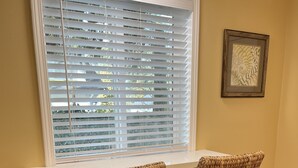 A dining area with two woven chairs, a white table, and a window with blinds. - Sequim Getaway (Sequim)