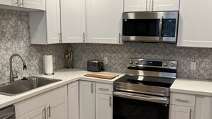 A modern kitchen with white cabinets, stainless steel appliances, a microwave, an oven, and a toaster. - Sequim Getaway (Sequim)