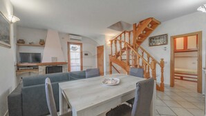 A cozy living area with a sofa, dining table, and a wooden staircase. - IL BORGHETTO - VILLINO IL BORGHETTO (Campo nell'Elba)