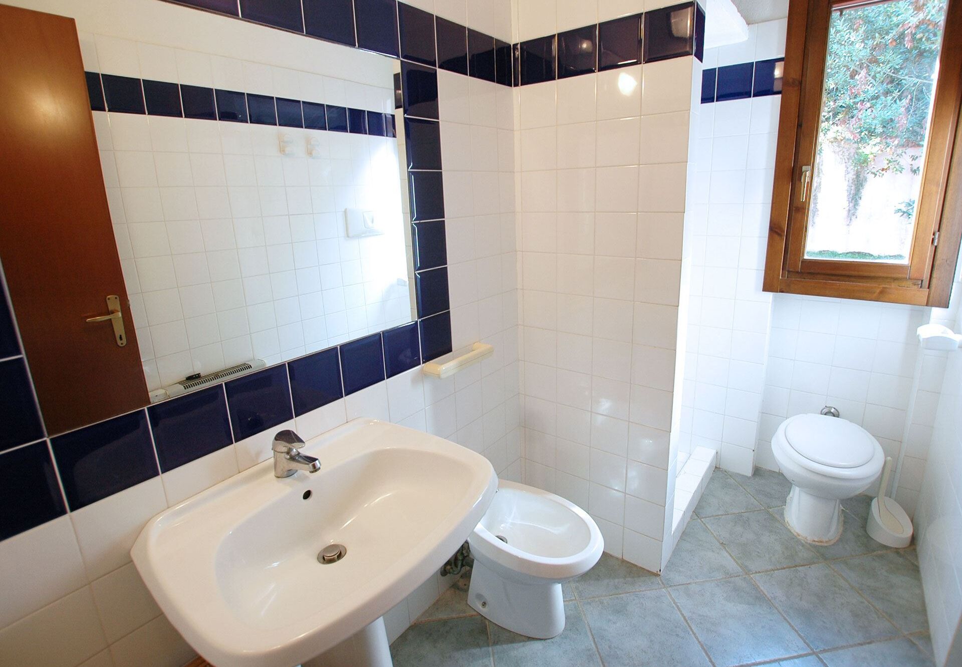 A bathroom with a sink, toilet, and bidet.