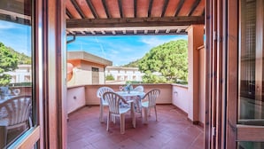 A balcony with a table and chairs, a pergola, and a view of greenery and buildings in the background. - Appartamenti Arcipelago - Appartamenti Arcipelago - Bilocale (27) (Rio dell'Elba)