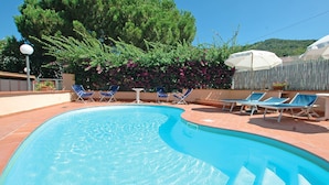 A swimming pool with blue water, surrounded by lounge chairs and a wooden fence. - Appartamenti Arcipelago - Appartamenti Arcipelago - Bilocale (27) (Rio dell'Elba)