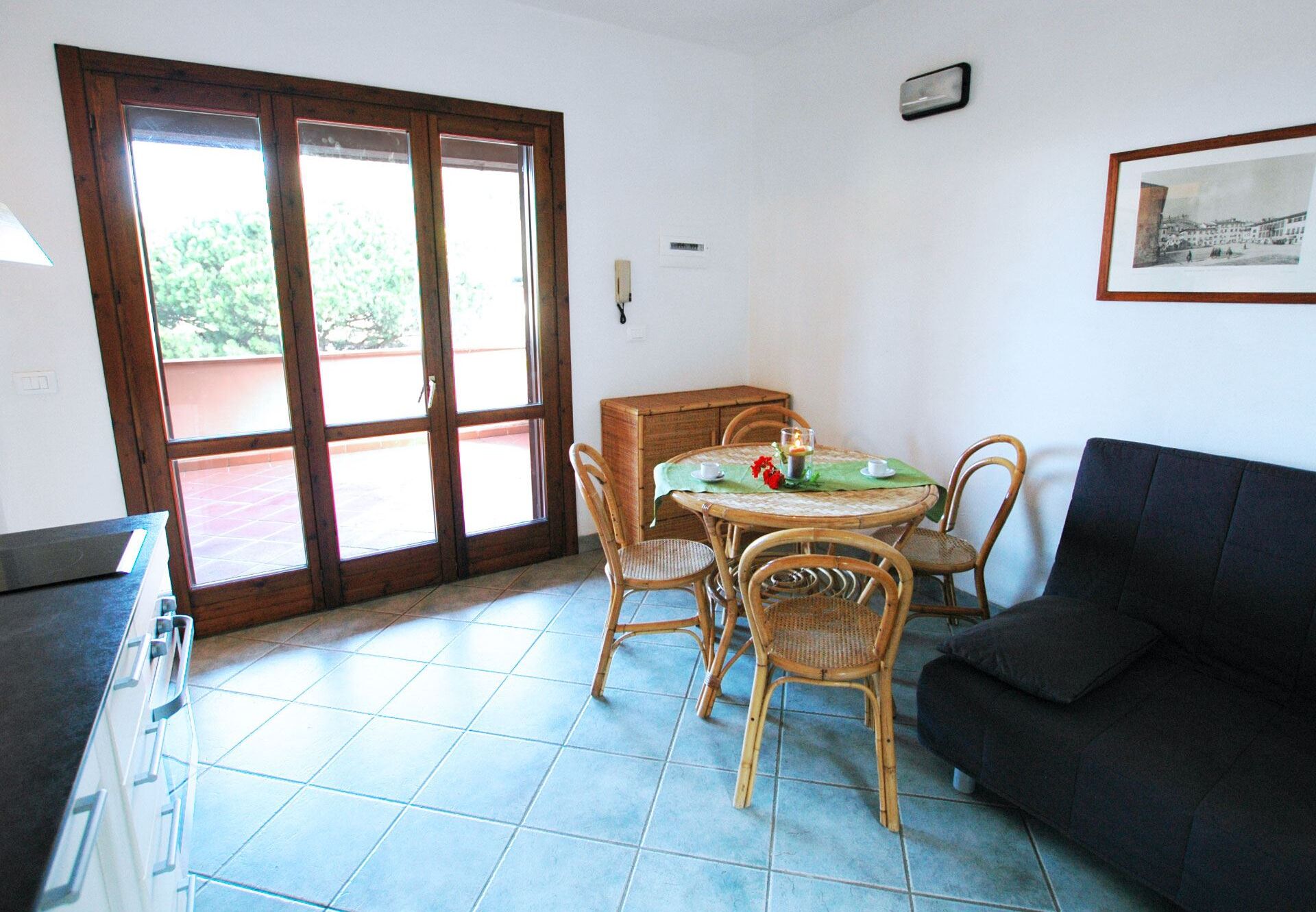 A dining area with a round table, four chairs, and a black sofa.