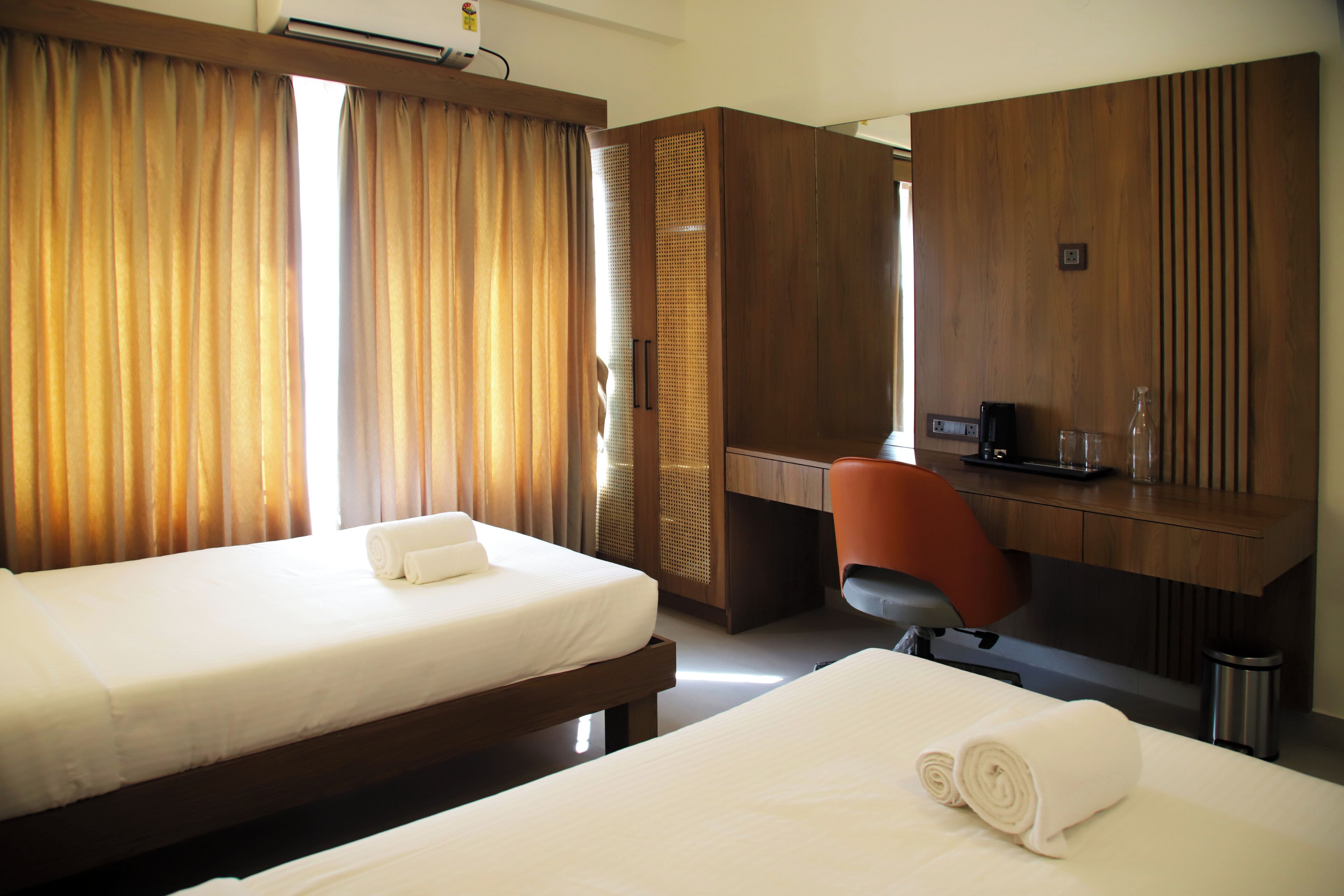 Habitación de hotel con dos camas, un escritorio de madera, una silla y un minibar.