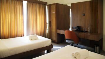 Habitación de hotel con dos camas, un escritorio de madera, una silla y un minibar.