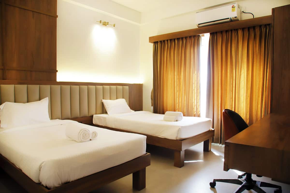 A hotel room with two beds, a desk, and a chair.