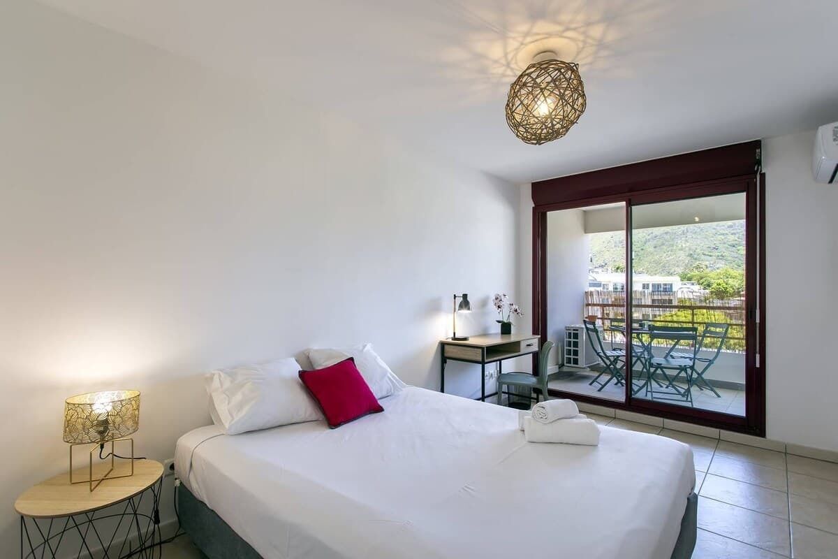 Ein Hotelzimmer mit Bett, Schreibtisch, Stuhl, Tisch und einem Balkon mit Aussicht.