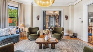 A spacious living room with a large sofa, two armchairs, a coffee table, and a chandelier. - The Royce on Pelham - Luxury Family Estate (Newport)