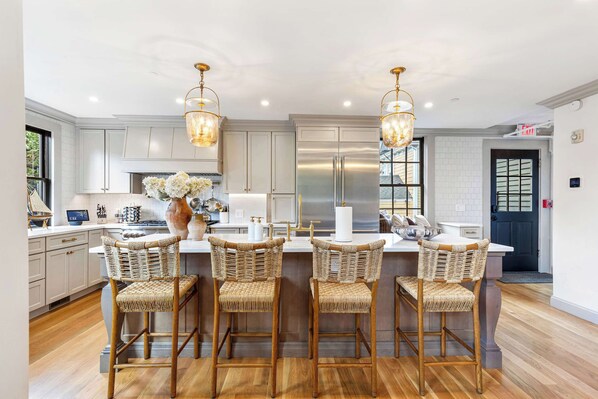 A modern kitchen with white cabinetry, stainless steel appliances, and a central island with bar stools.