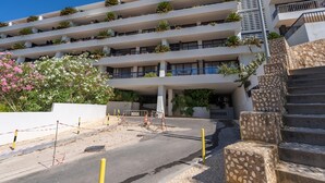 A multi-story hotel with balconies, a staircase, and a landscaped area with plants and flowers.