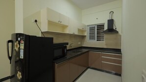 Μια μικρή, λειτουργική κουζίνα με ψυγείο, φούρνο μικροκυμάτων, νεροχύτη και ντουλάπια.