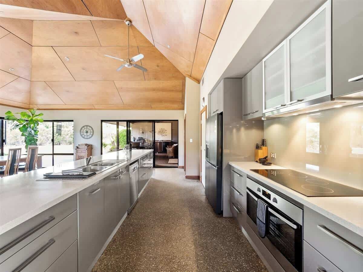 A modern kitchen with a central island, stainless steel appliances, and a ceiling fan.