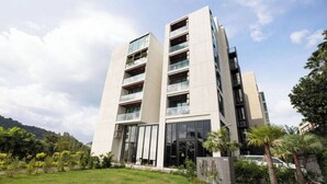 A modern multi-story building with balconies, large windows, and a well-maintained lawn. - Tropical View Apartment Viva Patong A601 (Patong)