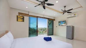 A hotel room with a large bed, ceiling fans, a balcony with a view, and an air conditioning unit. - Tropical View Apartment Viva Patong A601 (Patong)