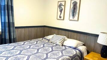 Una habitación de hotel con una cama, una mesita de noche y dos cuadros en la pared.