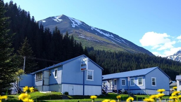 A two-story building with a blue exterior, a visible sign, and a staircase leading to the entrance. - The Tides Inn (Seward)