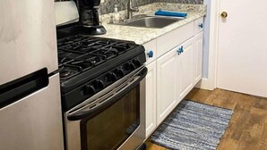 A kitchen with a refrigerator, stove, microwave, sink, and cabinets. - The Tides Inn (Seward)