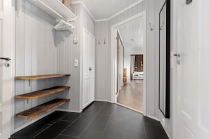 A hallway with white walls, black flooring, and wooden shelves. - Ski-in/Ski-out apartment with Sauna in Trysil REF:TH720 (Trysil)