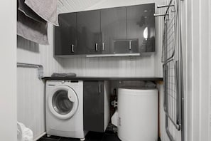 A compact laundry area with a front-loading washing machine, a dryer, and a metal rack. - Ski-in/Ski-out apartment with Sauna in Trysil REF:TH720 (Trysil)