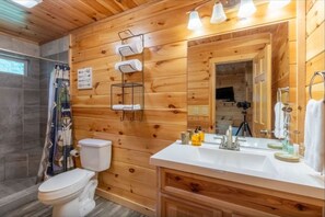 A wooden cabin bathroom with a toilet, sink, and shower. - Experience comfort in Bryson City at Smoky Ridge (Bryson City)