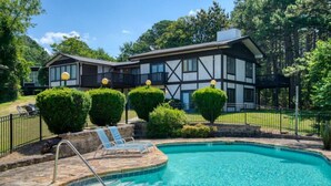Ein zweistöckiges Haus mit Schwimmbad, umgeben von einem Zaun und gepflegten Büschen.