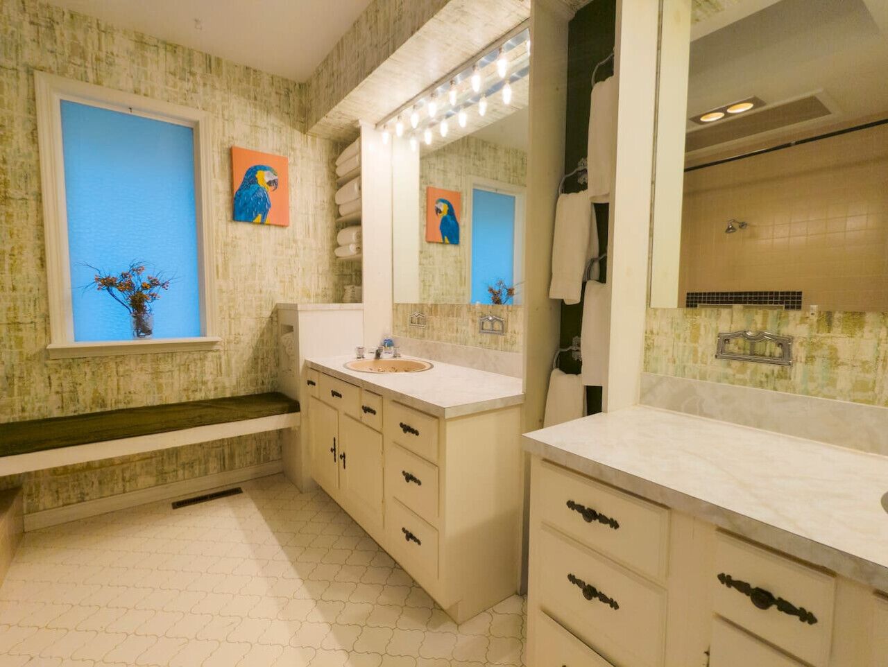 A bathroom with a large mirror, a sink, and a shower. There are two wall-mounted lights above the mirror.