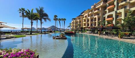 Una piscina de resort con agua cristalina, palmeras y vista al océano.