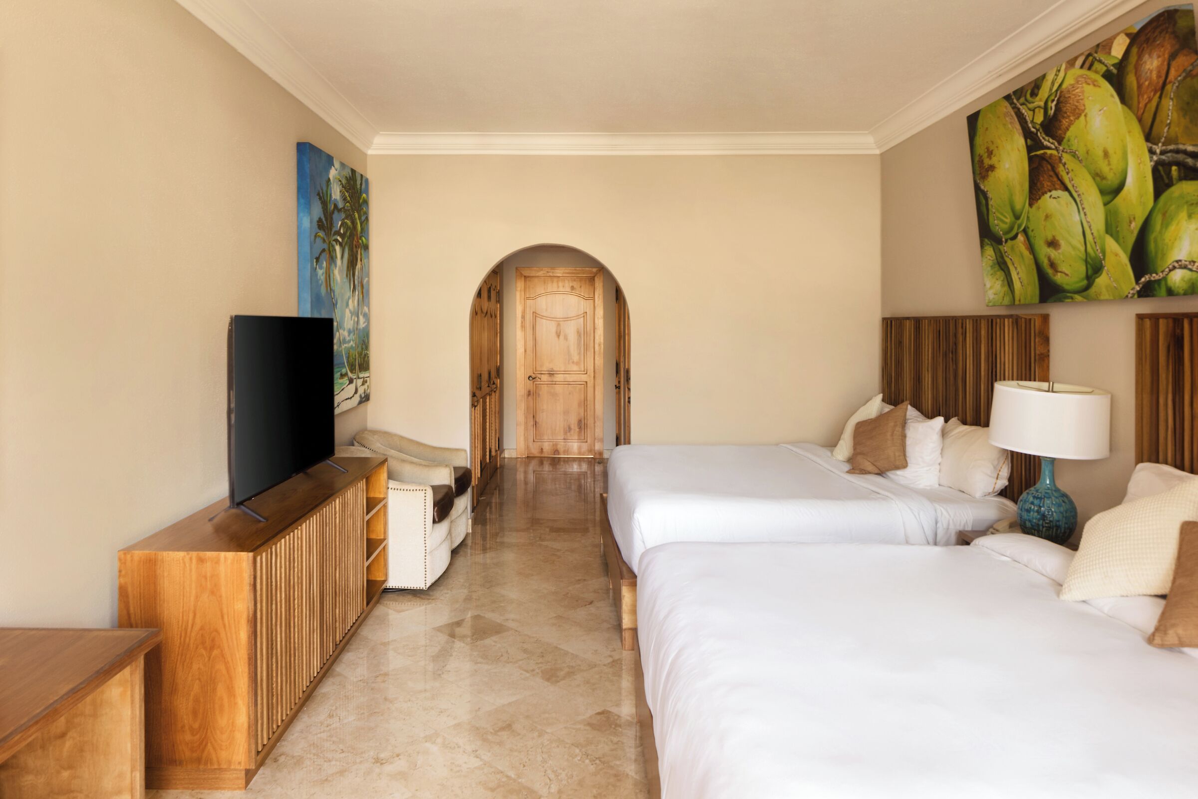 A hotel room with two beds, a TV, a wooden cabinet, and a painting on the wall.