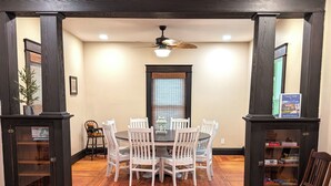 Un coin repas avec une table ronde et des chaises, un plancher en bois et un ventilateur de plafond.