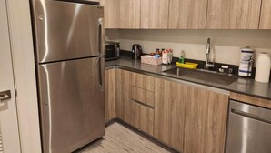 Une cuisine moderne avec des meubles en bois, des appareils en acier inoxydable et un plan de travail noir.