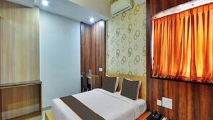 A modern hotel room with a large bed, a desk, and a wardrobe. - Coastal Grand - COIMBATORE (Coimbatore)