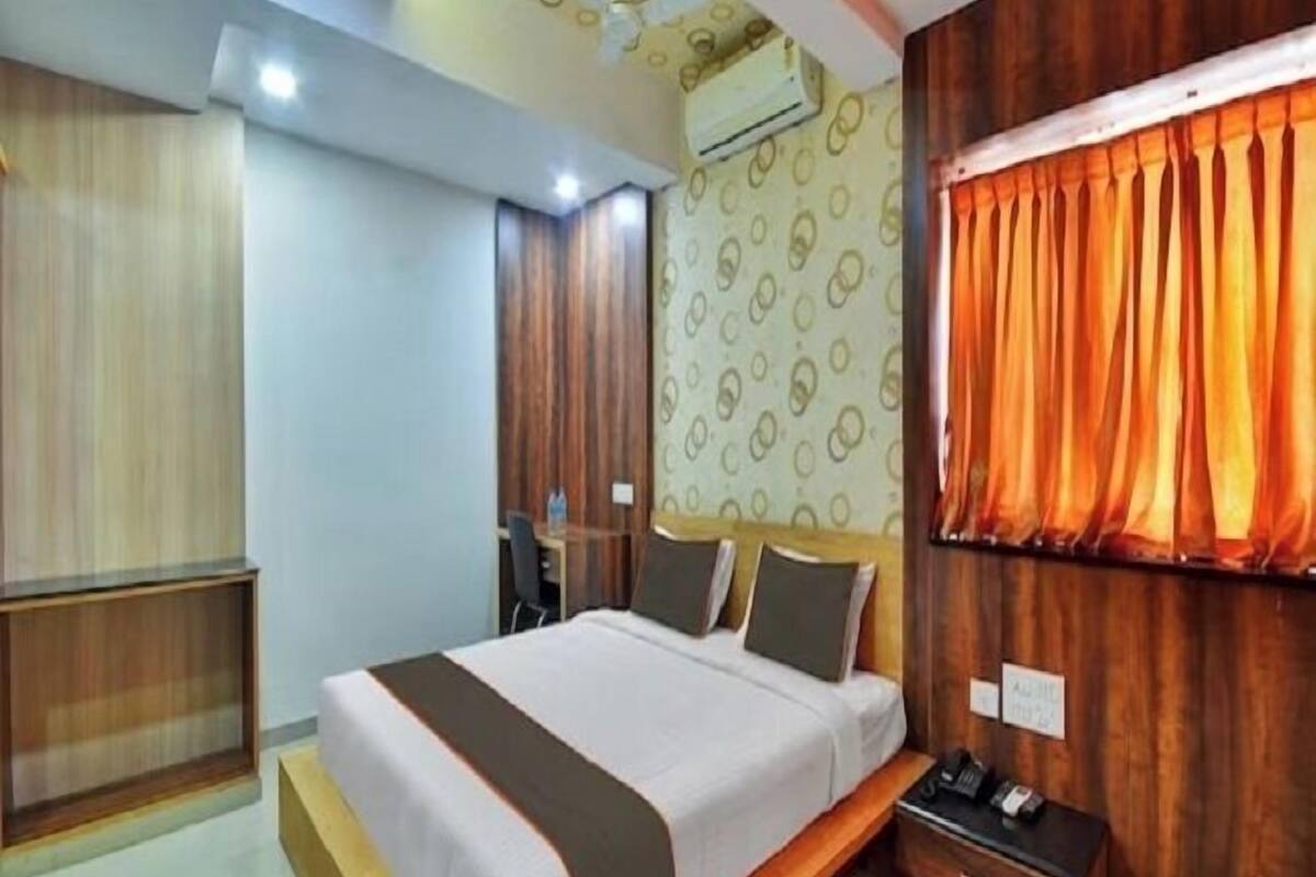A modern hotel room with a large bed, a desk, and a wardrobe.