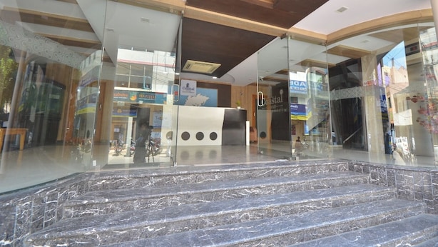 A modern hotel lobby with a reception desk, glass walls, and a marble staircase. - Coastal Grand - COIMBATORE (Coimbatore)