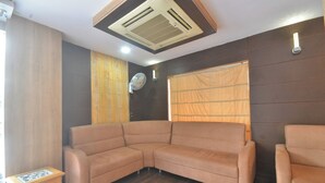 A modern living room with a sectional sofa, a small wooden table, and a ceiling fan. - Coastal Grand - COIMBATORE (Coimbatore)