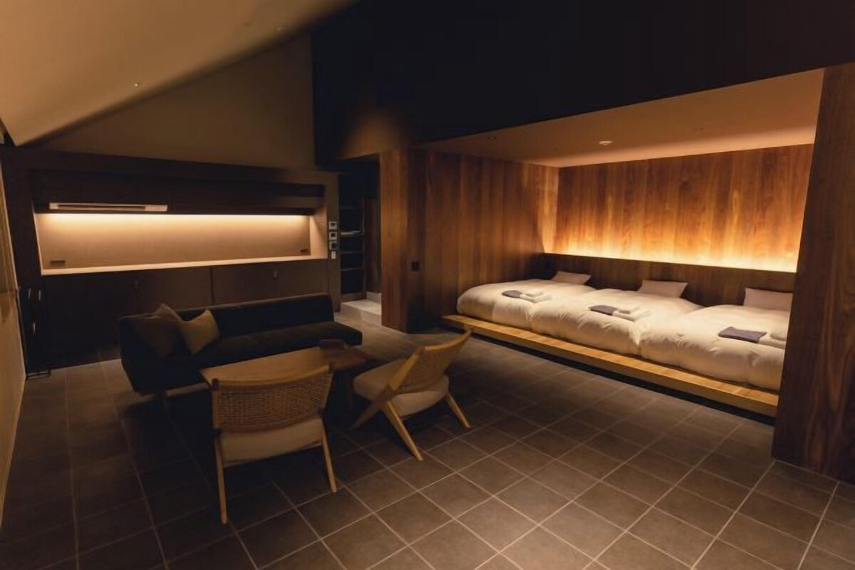 Quarto moderno com cama, mesas de cabeceira, um sofá e uma cadeira.