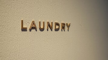 Das Wort "LAUNDRY" aus Holzlettern an einer strukturierten Wand.