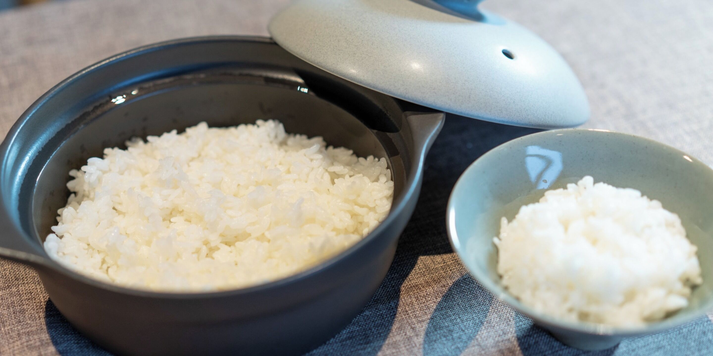 A bowl of white rice with a lid and a smaller bowl beside it.