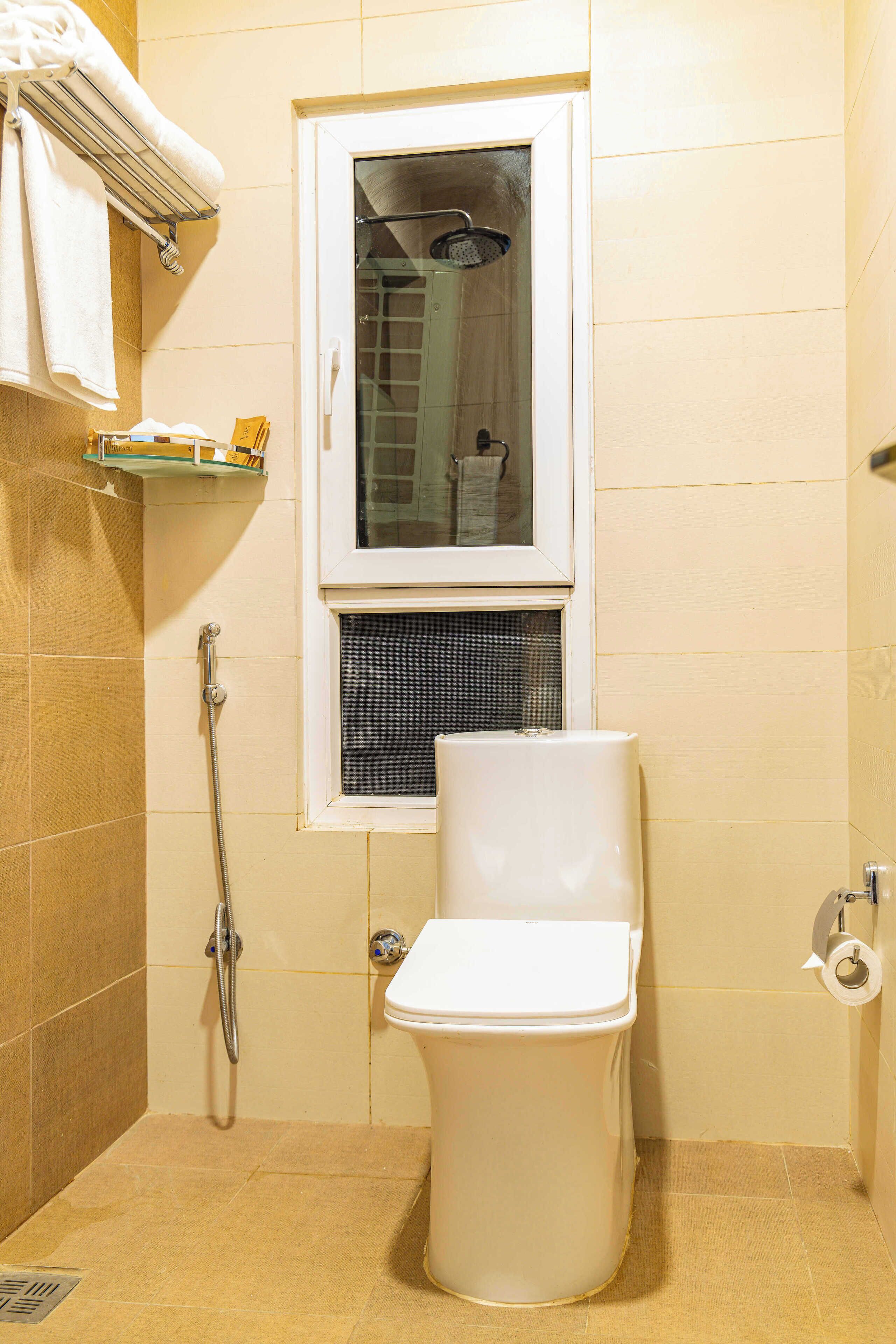 Et lille badeværelse med toilet, brusebad og et vindue.