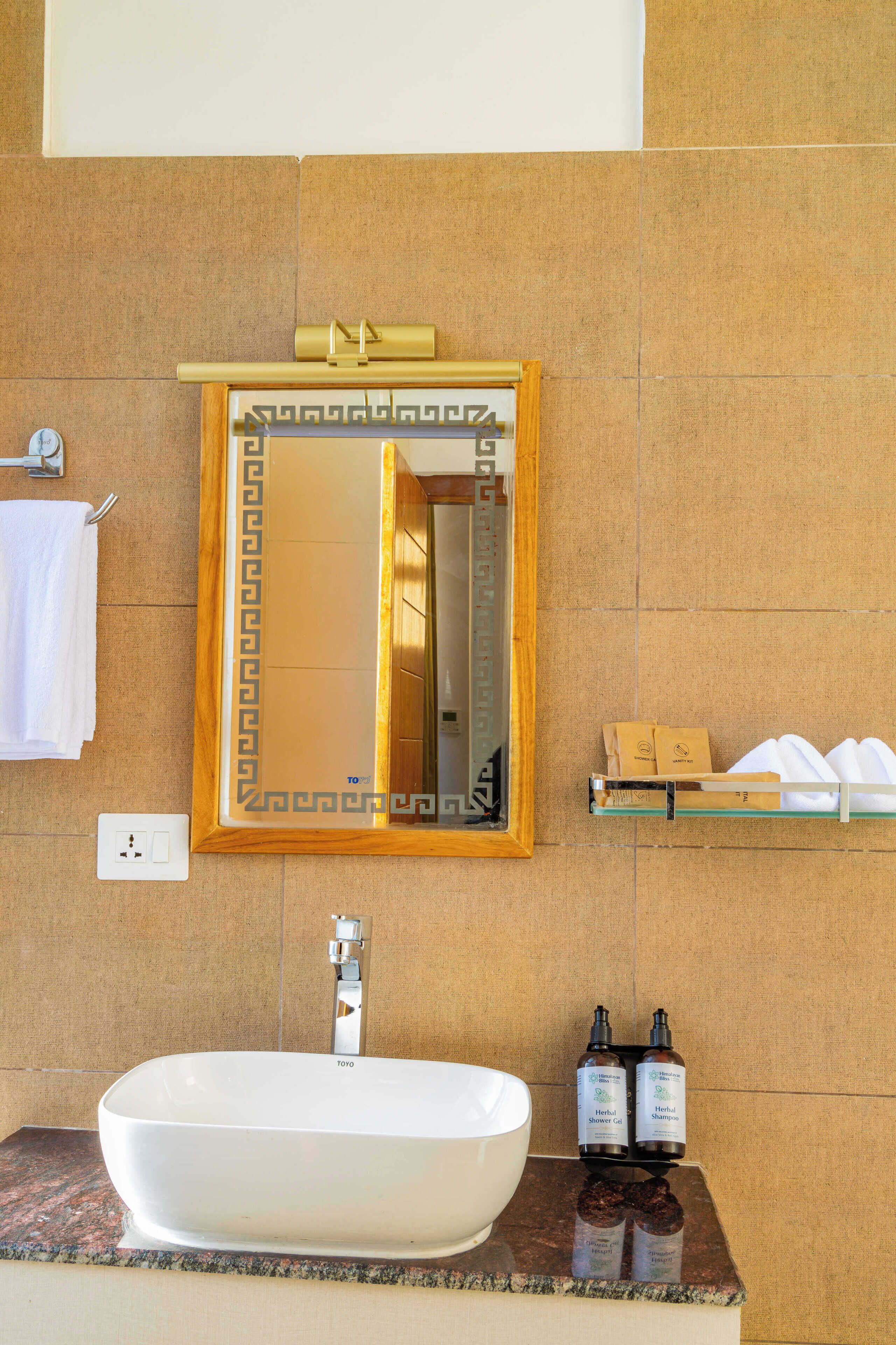 A bathroom with a white sink, a mirror with a decorative frame, and a shelf with toiletries.