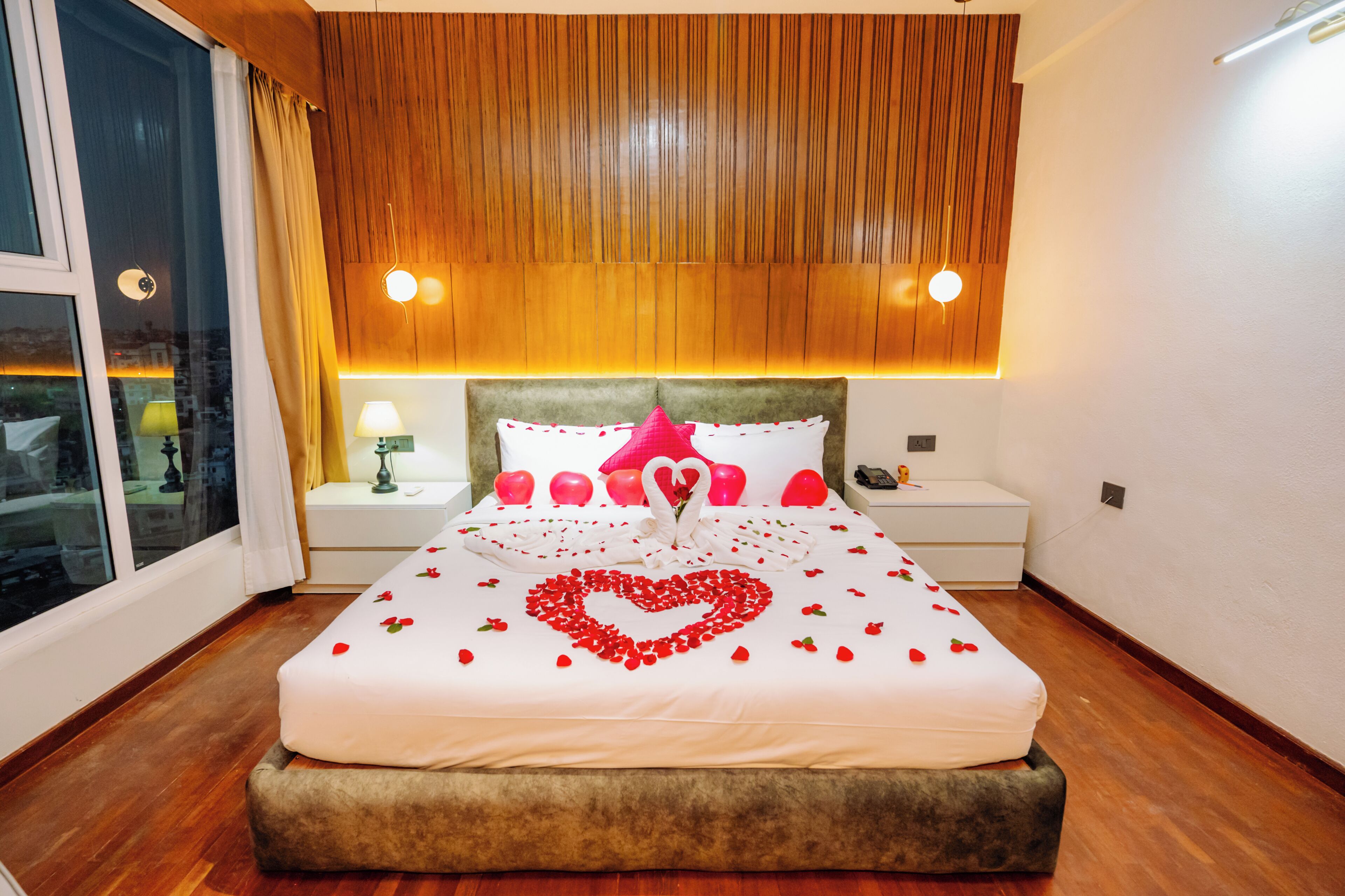 A neatly made bed with a heart-shaped decoration, a bedside lamp, and a wooden headboard.