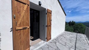 A building with wooden doors and a stone-paved entrance area. - A hiking and nature break in the heart of the Southern Cévennes.  On the menu: garden, peace and space. (Montdardier)