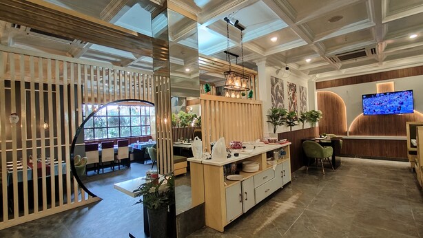 A modern restaurant with a high ceiling, wooden partitions, and a large window. - Hotel Holiday international (Purnia)